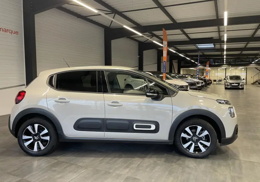 Vue de profil côté gauche d'une Citroën C3 beige clair avec Airbump noirs et jantes alliage diamantées en showroom.