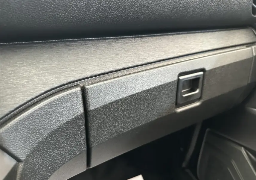 Désolé, je ne vois pas de véhicule bleu AIXAM AMBITION 0.5 CITY PACK dans cette image, mais un gros plan sur la boîte à gants intérieure noire.