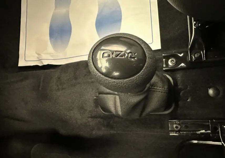 Gros plan sur le levier de vitesses noir de l'AIXAM AMBITION 0.5 CITY PACK 2026, intérieur sombre sans couleur visible.