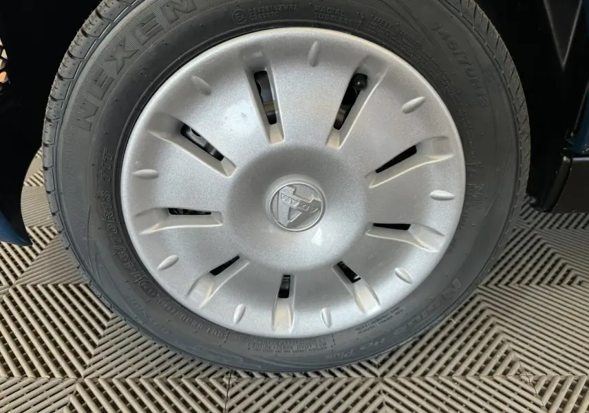 Gros plan sur la roue avant droite de l'AIXAM AMBITION 0.5 CITY PACK bleu, avec enjoliveur argenté et logo central.