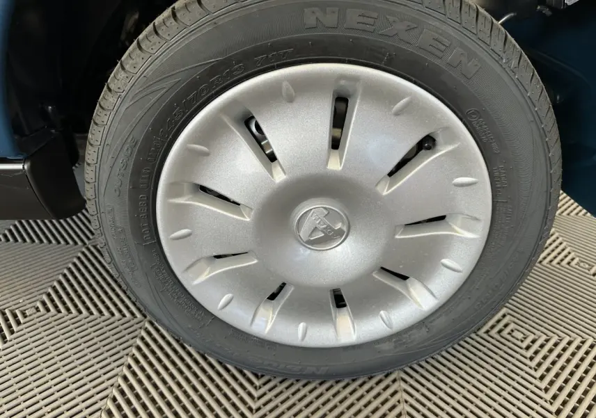 Gros plan sur la roue avant droite avec enjoliveur argenté du véhicule bleu Aixam Ambition 0.5 City Pack 2026.