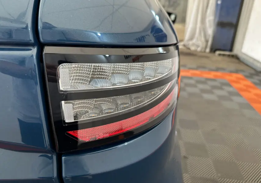 Gros plan sur le feu arrière droit bleu de l'AIXAM AMBITION 0.5 CITY PACK 2026 avec détails lumineux nets.