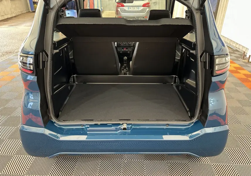 Coffre ouvert vu de l'arrière d'une Aixam Ambition 0.5 City Pack bleu 2026 avec rétroviseur caméra côté gauche.