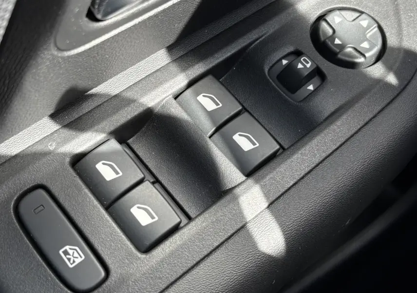 Gros plan sur les commandes de lève-vitres et réglage des rétroviseurs côté conducteur d'une Citroën C4 Hybrid 2025.