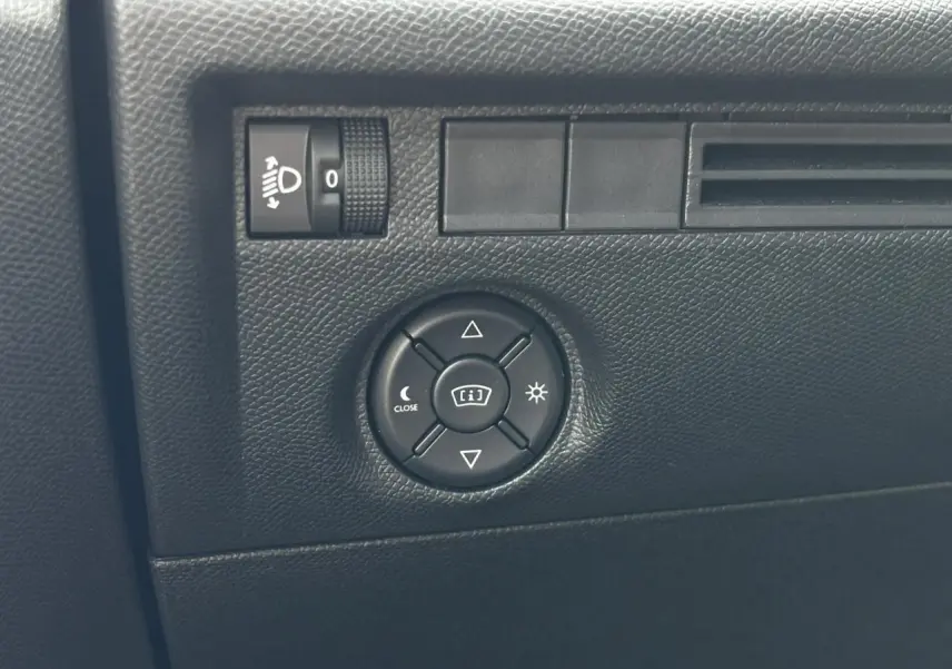 Gros plan sur les commandes d’éclairage et réglage du tableau de bord dans l’habitacle noir du Citroën C4 Hybrid 2025.