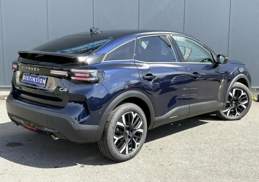Vue 3/4 arrière droite d'une Citroën C4 Hybrid 145 bleu Eclipse avec jantes alliage 18'' et toit noir brillant.