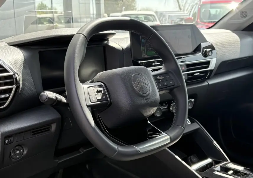 Vue intérieure centrée sur le volant cuir noir et le tableau de bord moderne du Citroën C4 Hybrid 2025.