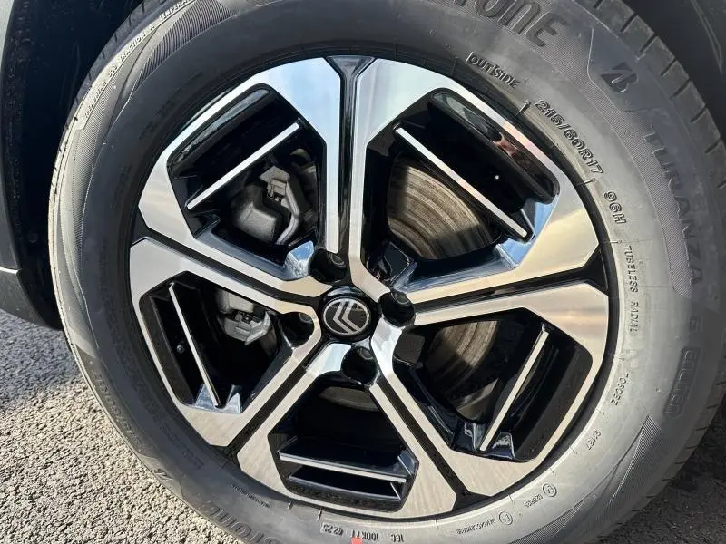 Gros plan sur la jante alu noire et argentée du Citroën C3 Aircross noir, montrant le logo Citroën au centre.