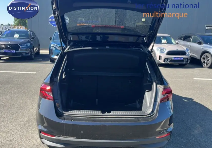Vue arrière d'une Skoda Fabia 2025 noir magique métal avec coffre ouvert sur parking extérieur.
