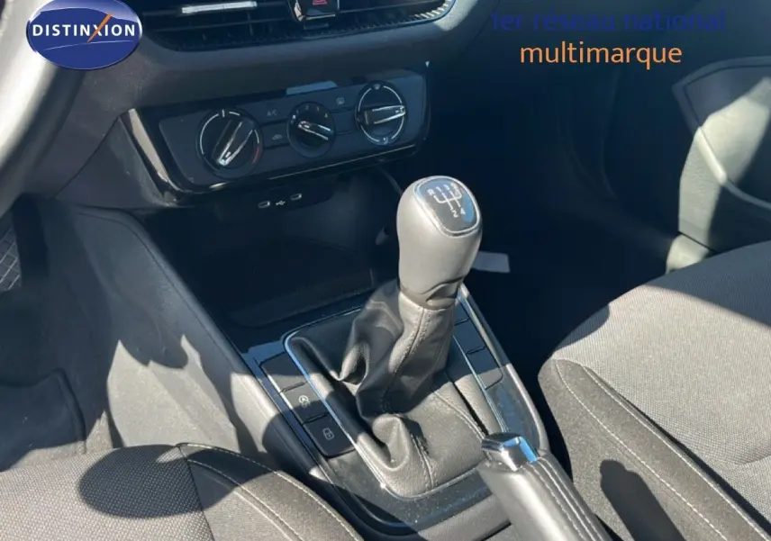 Gros plan intérieur sur la console centrale d'une Skoda Fabia noire, montrant la boîte manuelle et les commandes de climatisation.