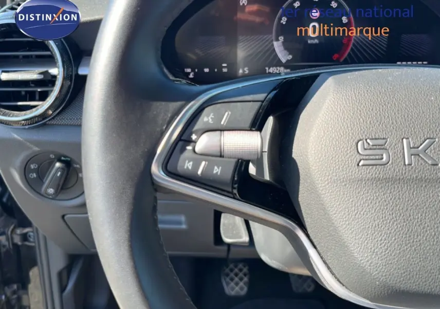 Gros plan sur le volant noir et le tableau de bord digital d'une Skoda Fabia 2025, avec commandes multifonctions visibles.