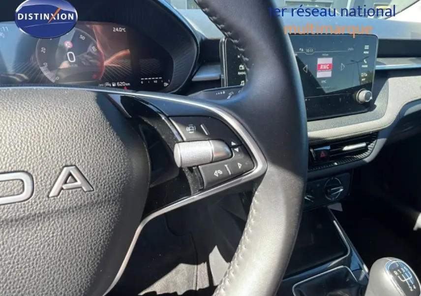 Vue intérieure centrée sur le volant et le tableau de bord d’une Skoda Fabia noire avec boîte manuelle et écran tactile.
