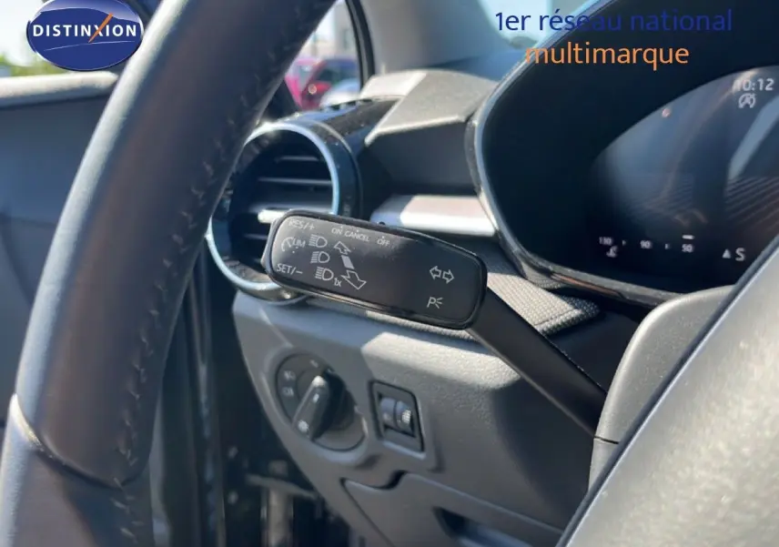Gros plan sur la commande de régulateur de vitesse à gauche du volant dans l’habitacle d’une Skoda Fabia noir magique métal.
