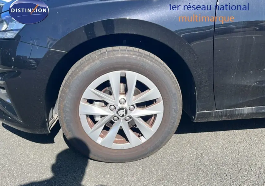 Gros plan sur la roue avant gauche d’une Skoda Fabia noire métallique, mettant en valeur la jante argentée et le logo central.