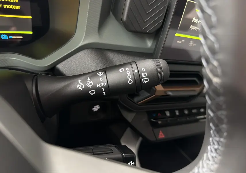 Gros plan sur la commande d’essuie-glace à gauche du volant dans l’habitacle du Dacia Bigster Hybrid 155 bleu indigo.