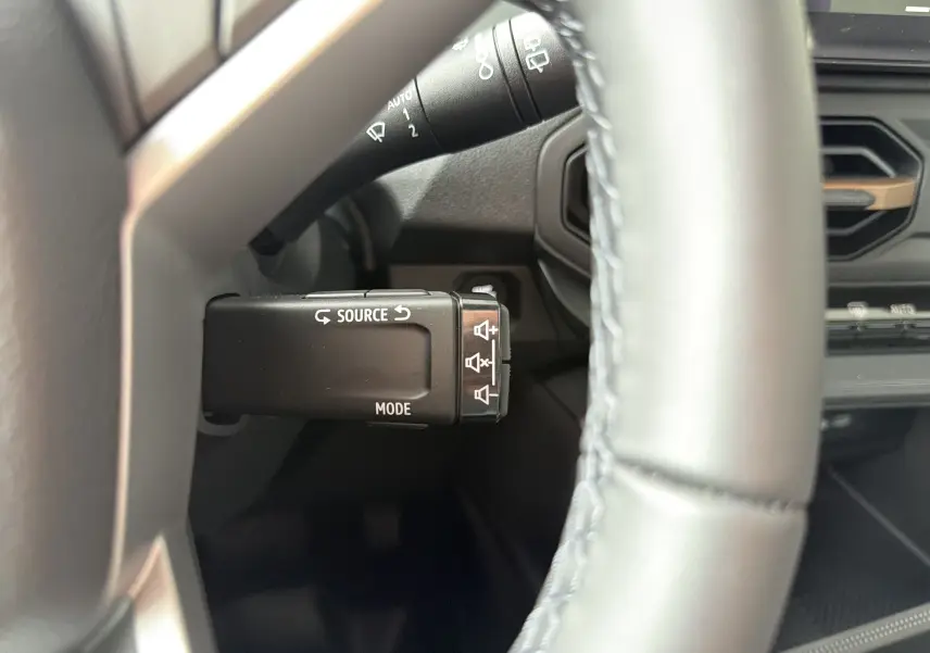 Gros plan sur la commande multimédia au volant du Dacia Bigster Hybrid 155 Extreme, intérieur noir et détails fonctionnels visibles.