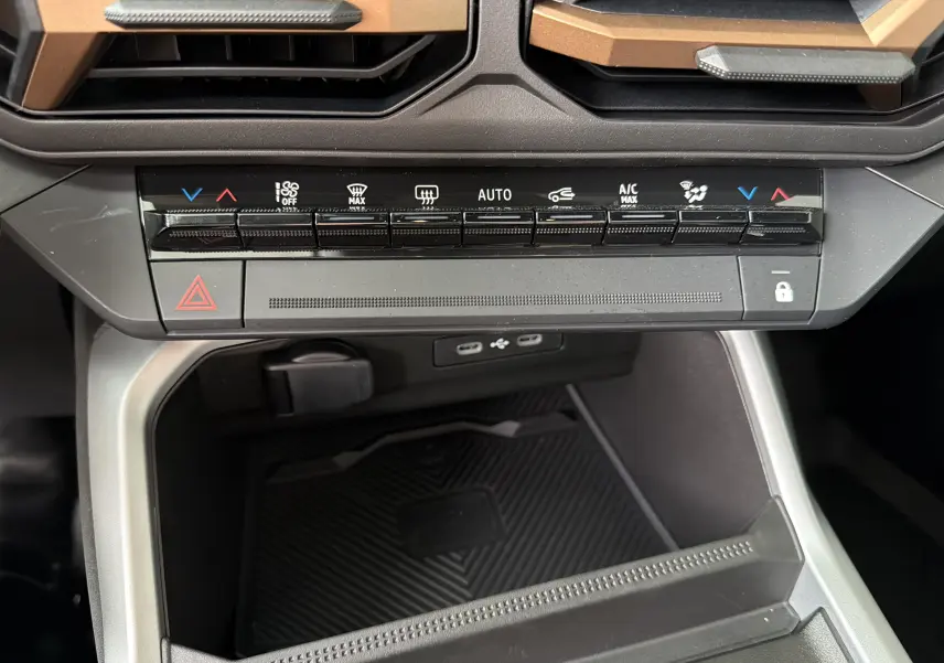 Gros plan sur la console centrale du Dacia Bigster Hybrid 155 Extreme, montrant les commandes de climatisation et ports USB.