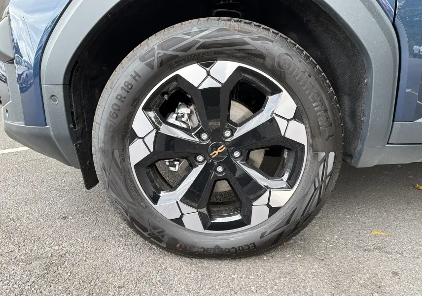 Gros plan sur la roue avant droite du Dacia Bigster Hybrid 155 Extreme bleu indigo avec jante alliage diamantée 18 pouces.