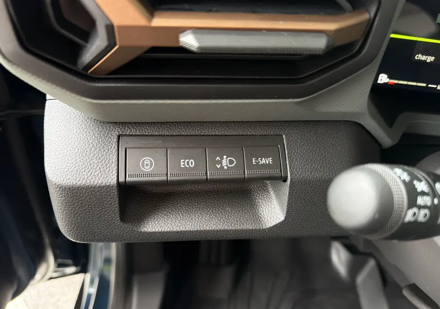 Détail intérieur du tableau de bord du Dacia Bigster Hybrid 155 Extreme bleu indigo, avec boutons de contrôle ECO et E-SAVE.