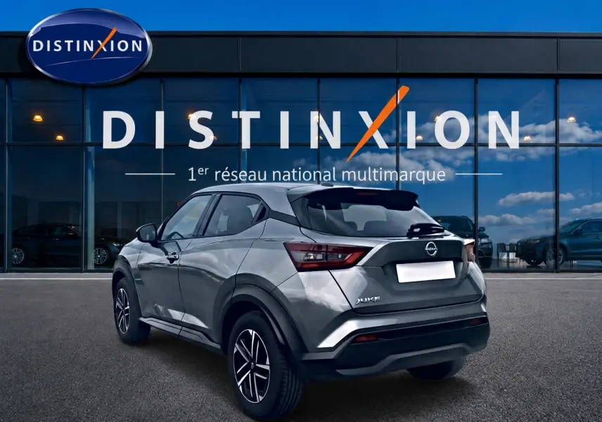 Nissan Juke gris vue 3/4 arrière droit, avec jantes alu et feux arrière LED, devant un showroom Distinxion.