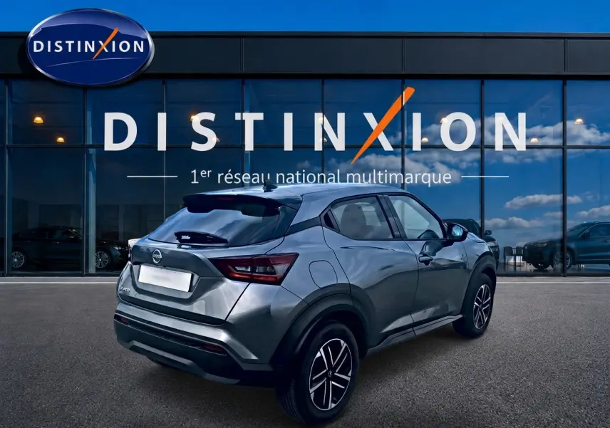 Nissan Juke gris 3/4 arrière droit, avec jantes alu et feux arrière LED, devant une vitrine Distinxion.