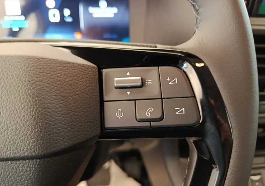 Gros plan sur les commandes multifonctions côté droit du volant du Peugeot Expert Fourgon XL noir, tableau de bord en arrière-plan flou.