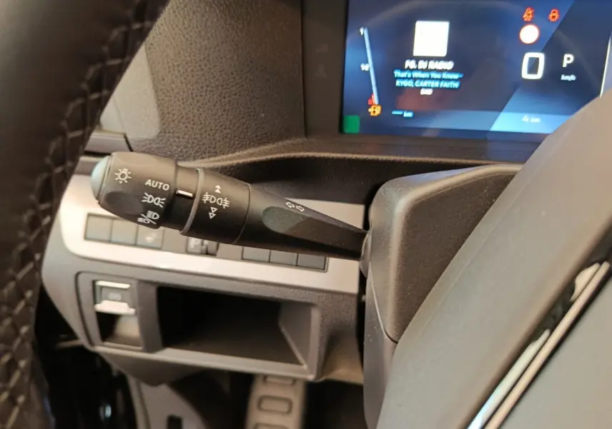 Gros plan sur la manette des phares et clignotants à gauche du volant du Peugeot Expert Fourgon noir, tableau de bord numérique visible.