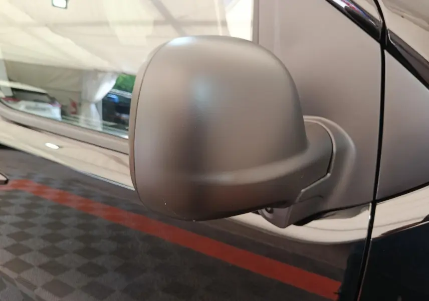 Gros plan sur le rétroviseur côté conducteur du Peugeot Expert Fourgon XL noir, avec reflet de l'environnement intérieur.