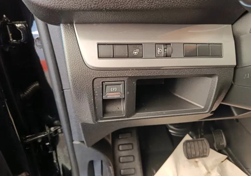 Détail intérieur côté gauche du Peugeot Expert Fourgon noir, montrant les commandes de frein à main électrique et réglage des phares.
