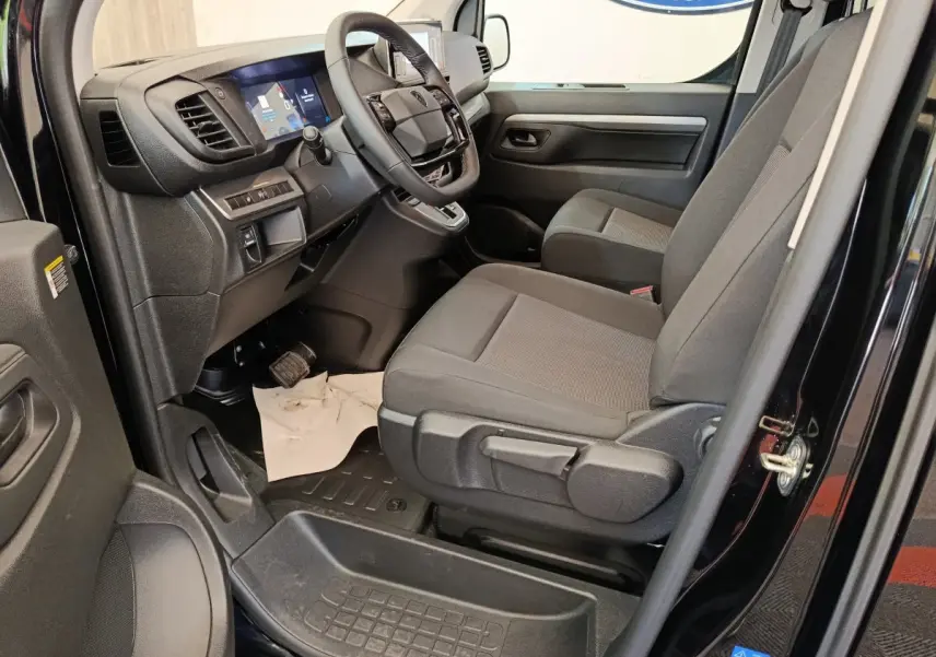 Vue intérieure côté conducteur du Peugeot Expert Fourgon XL noir, montrant le tableau de bord et les sièges avant gris.