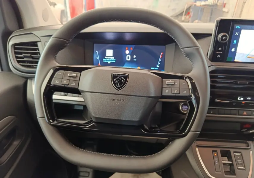 Vue rapprochée du volant noir multifonctions de la Peugeot Expert Fourgon XL avec tableau de bord digital en arrière-plan.