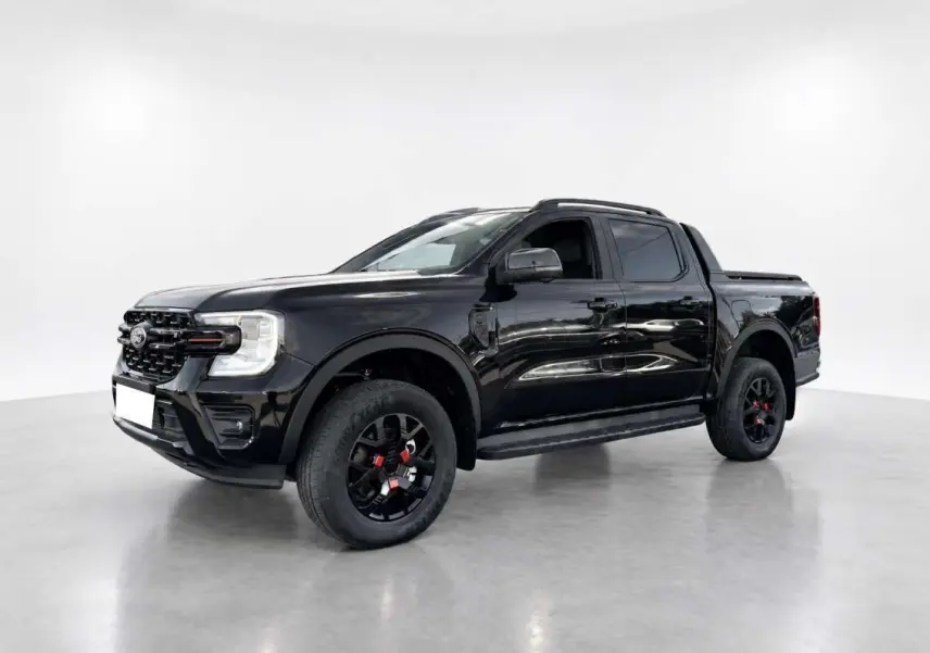 Ford Ranger Wildtrak Plus noir agate en 3/4 avant droit, avec jantes noires et barres de toit visibles.