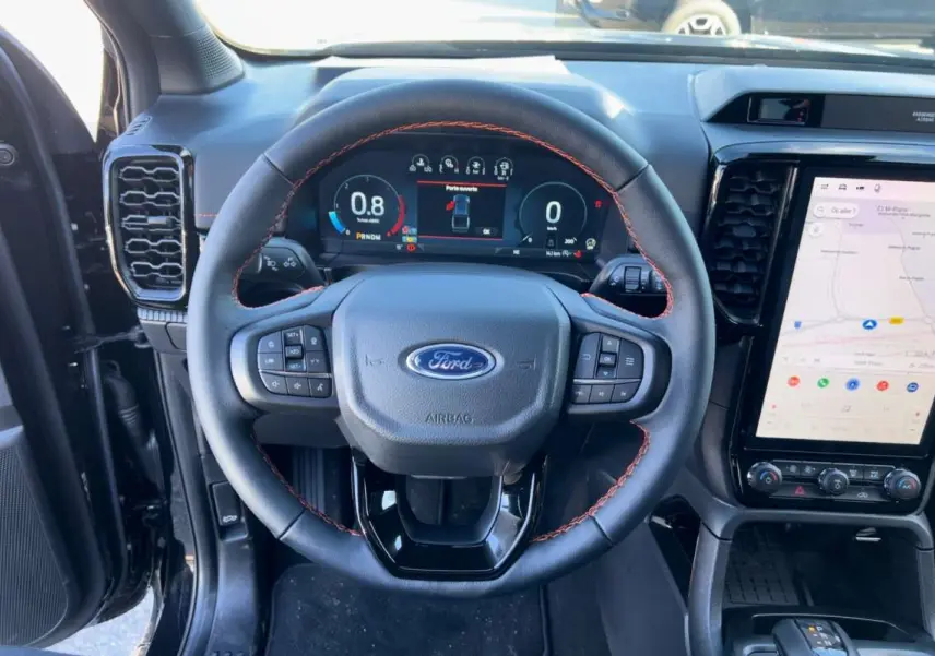 Vue intérieure centrée sur le volant cuir noir avec surpiqûres orange et écran tactile vertical du Ford Ranger 2026.