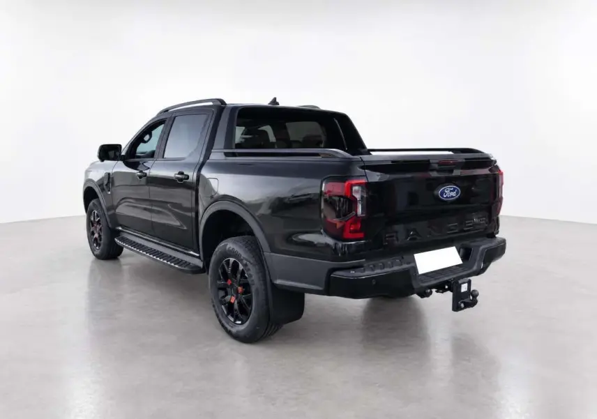 Ford Ranger Wildtrak noir agate vu en 3/4 arrière droit, avec attelage et jantes noires distinctives.