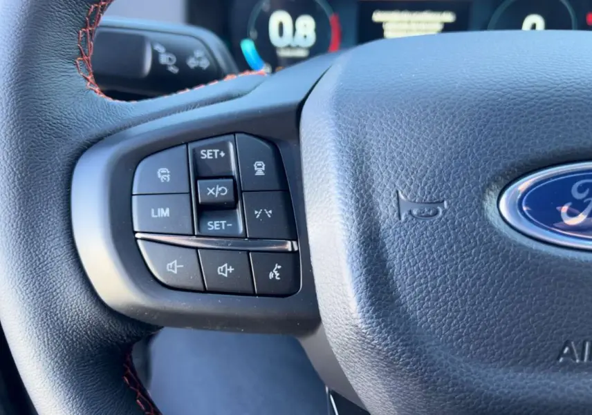 Gros plan sur le volant cuir multifonctions du Ford Ranger Wildtrak 2026 avec commandes intégrées et surpiqûres orange.