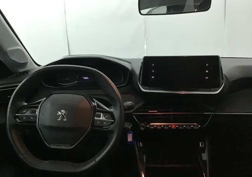 Intérieur de la Peugeot 208 noire 2022, vue du poste de conduite avec volant compact et écran tactile central.