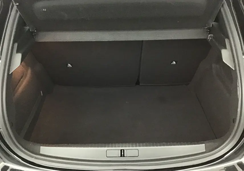 Coffre ouvert d'une Peugeot 208 noire, vue de dessus montrant un espace de chargement vide et propre.
