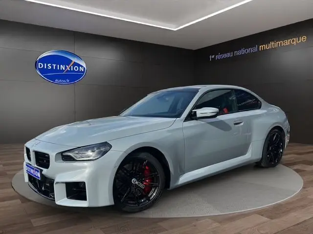 BMW M2 G87 gris Brooklyn vue 3/4 avant droit, jantes noires et étriers de frein rouges visibles