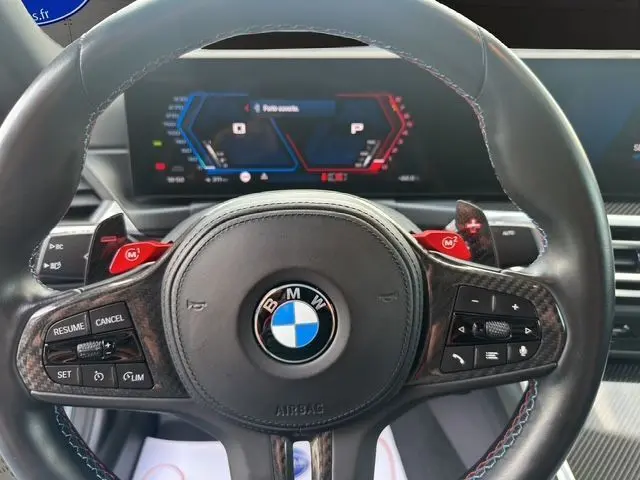 Vue rapprochée du volant en cuir noir avec surpiqûres tricolores et commandes M rouges de la BMW M2 G87 2024.