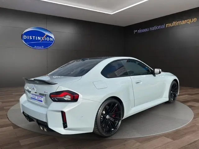 Vue 3/4 arrière droite d'une BMW M2 G87 gris Brooklyn Grau avec jantes noires et aileron sportif en showroom
