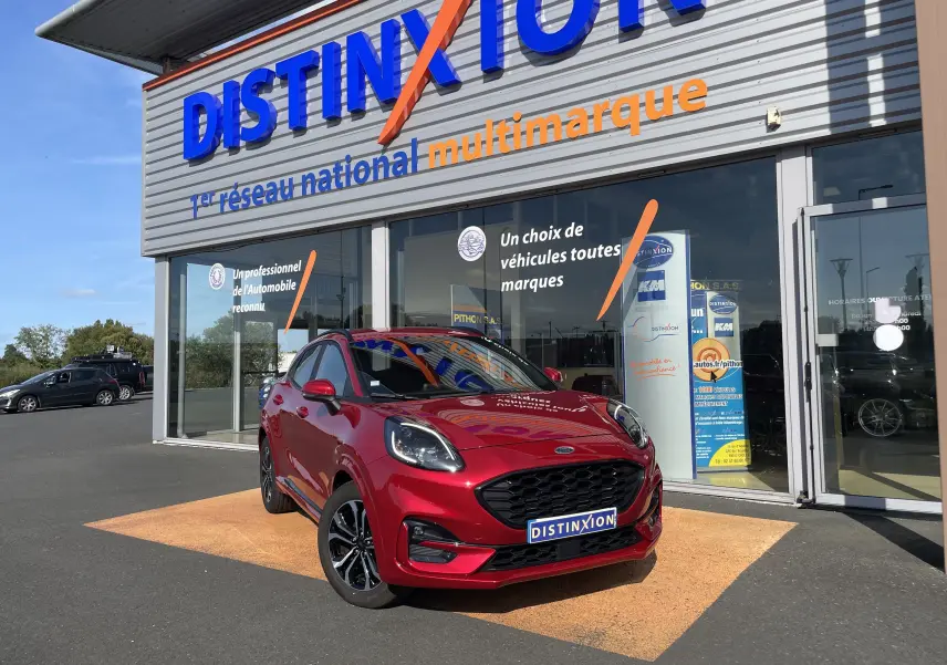 Ford Puma rouge vue 3/4 avant droit, garée devant un showroom avec logo Distinxion en arrière-plan.
