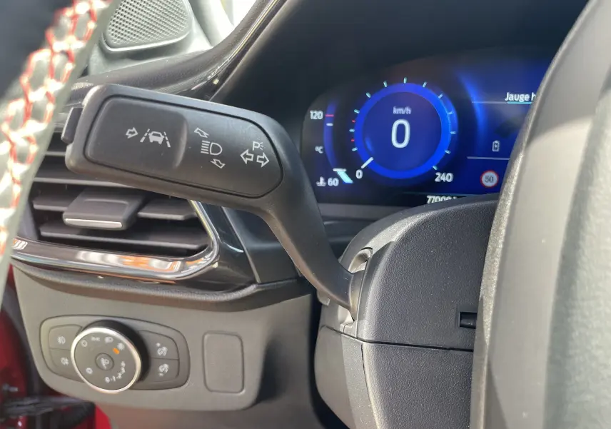 Vue rapprochée du combiné d'instruments et du commodo gauche du Ford Puma rouge 2021, avec affichage digital bleu.