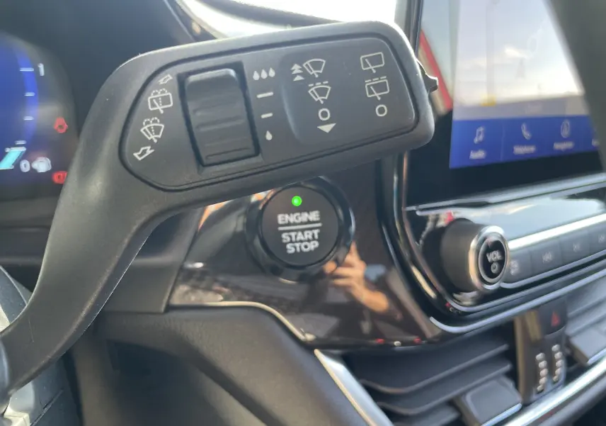 Détail du commodo d'essuie-glace et bouton start/stop sur le tableau de bord noir brillant d'un Ford Puma rouge 2021.
