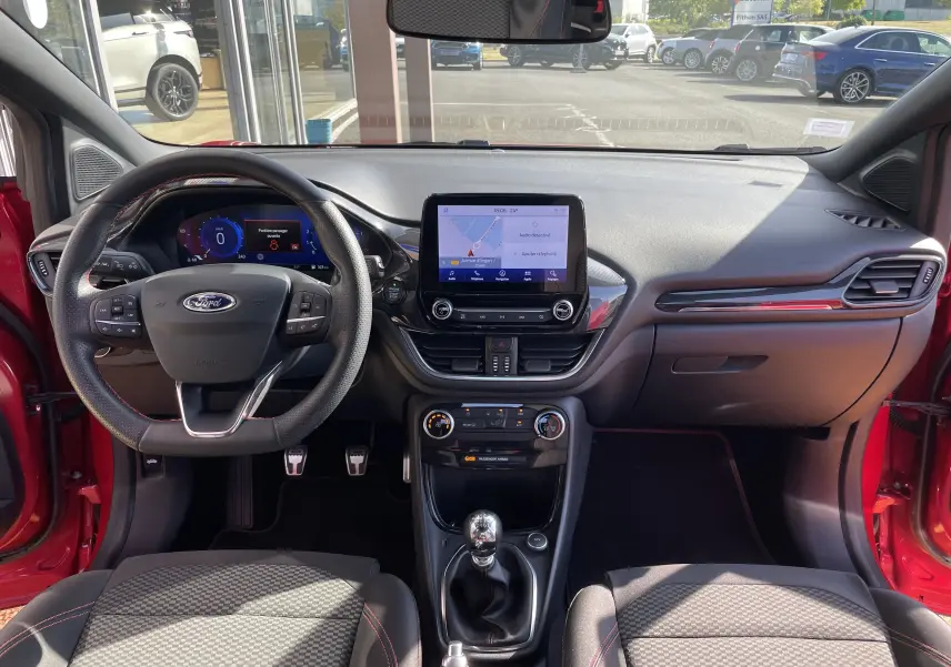 Vue intérieure avant du Ford Puma rouge 2021, tableau de bord avec écran tactile et volant multifonction noir.