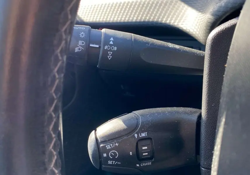 Gros plan sur la commande de régulateur de vitesse au volant cuir noir d'un Peugeot 2008 2019.