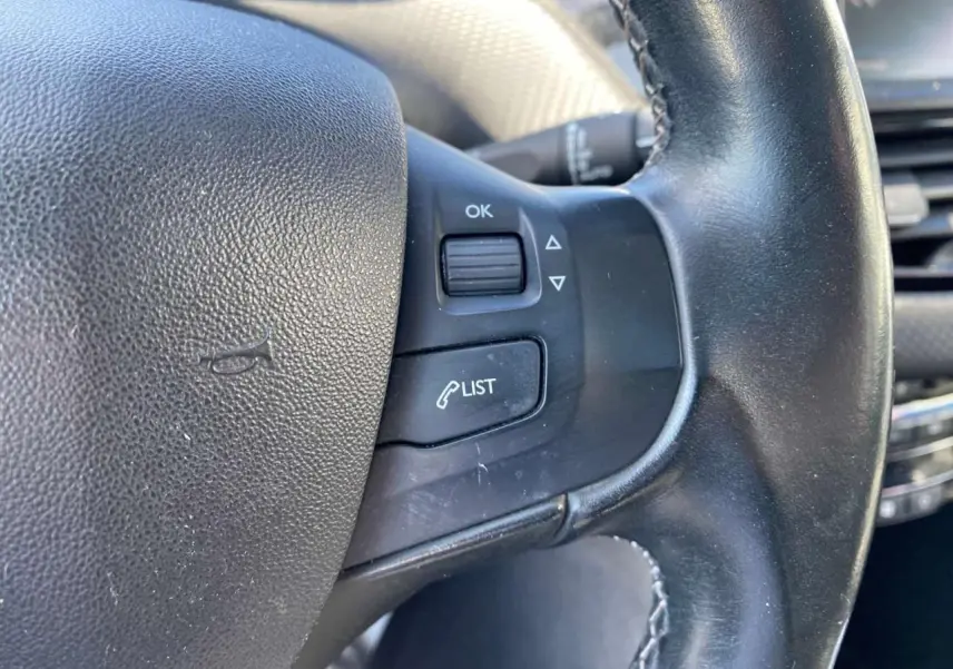 Gros plan sur le volant cuir noir du Peugeot 2008 2019 avec commandes multifonctions côté gauche.