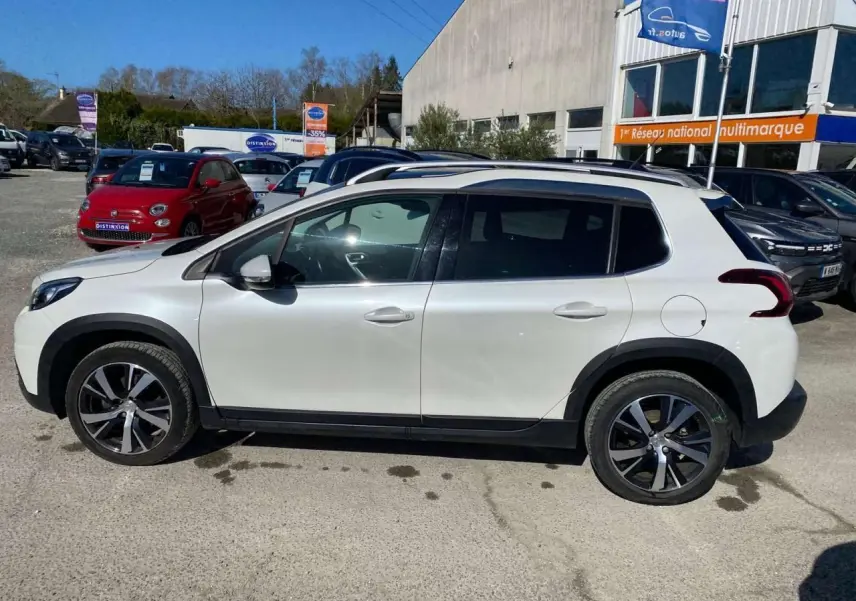 Peugeot 2008 essence 2019 vue de profil côté gauche, carrosserie blanche et jantes aluminium 17 pouces.