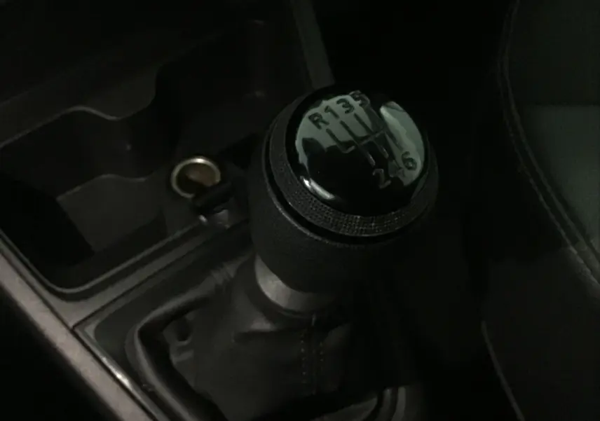 Gros plan sur le levier de vitesses manuel noir du Renault Express Van 2023, intérieur sombre et console centrale visible.