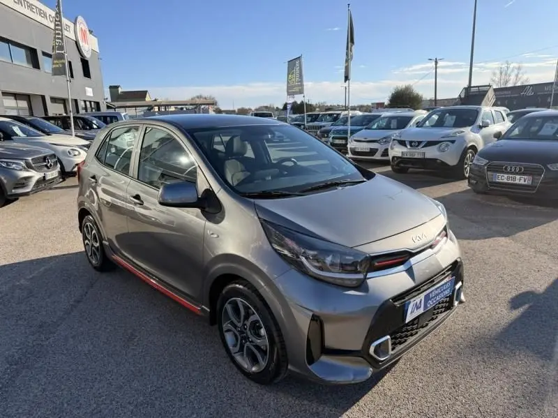 KIA Picanto 2023 gris foncé vue 3/4 avant droit, avec détails rouges GT Line sur la calandre et bas de caisse.