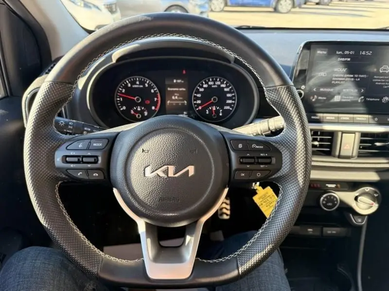 Vue intérieure centrée sur le volant KIA d'une Picanto 2023, avec tableau de bord et écran tactile visibles.